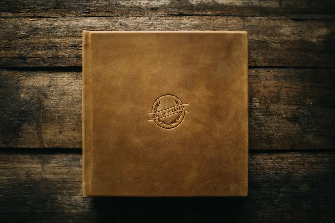 A gold-embossed fine art wedding album resting on timber