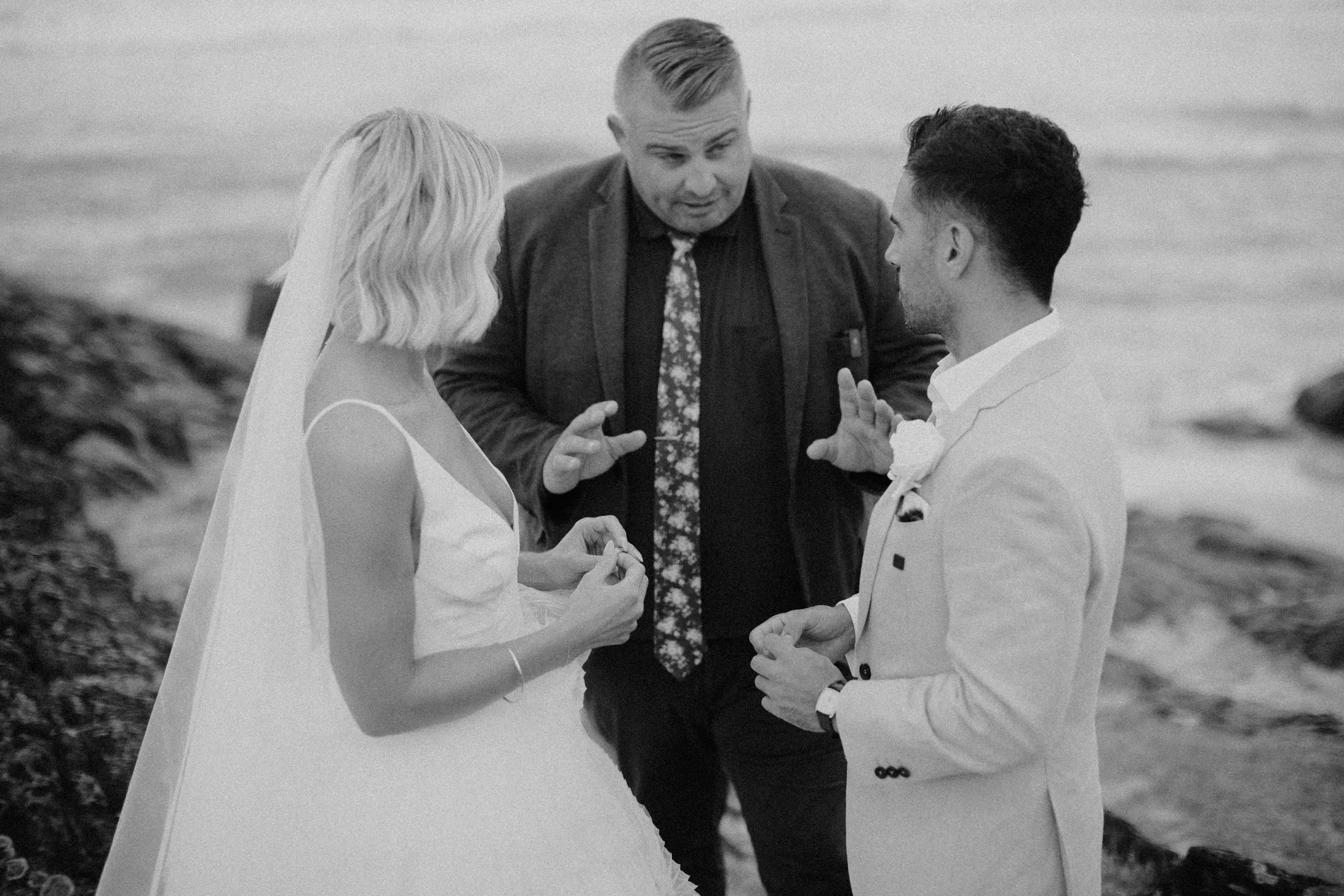 Black and white beach ceremony with celebrant and couple