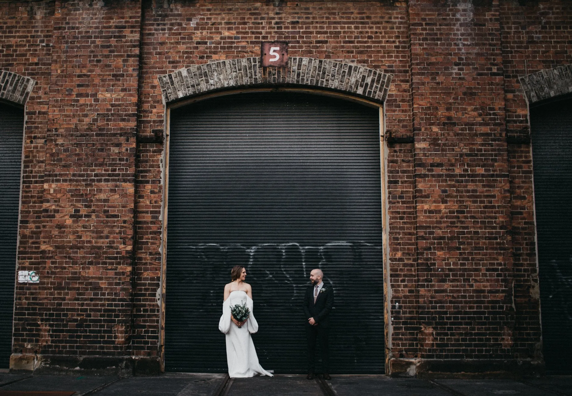 Couple dwarfed by a brick warehouse doorway