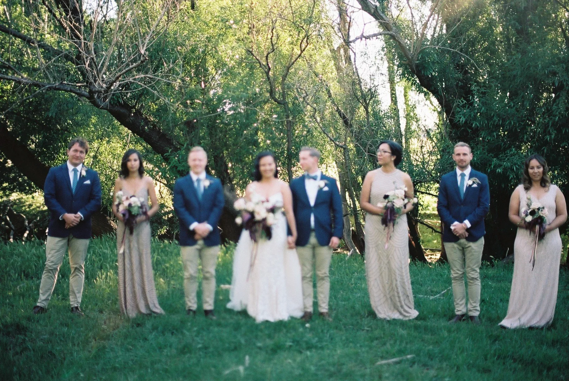 A bridal party standing together under old trees