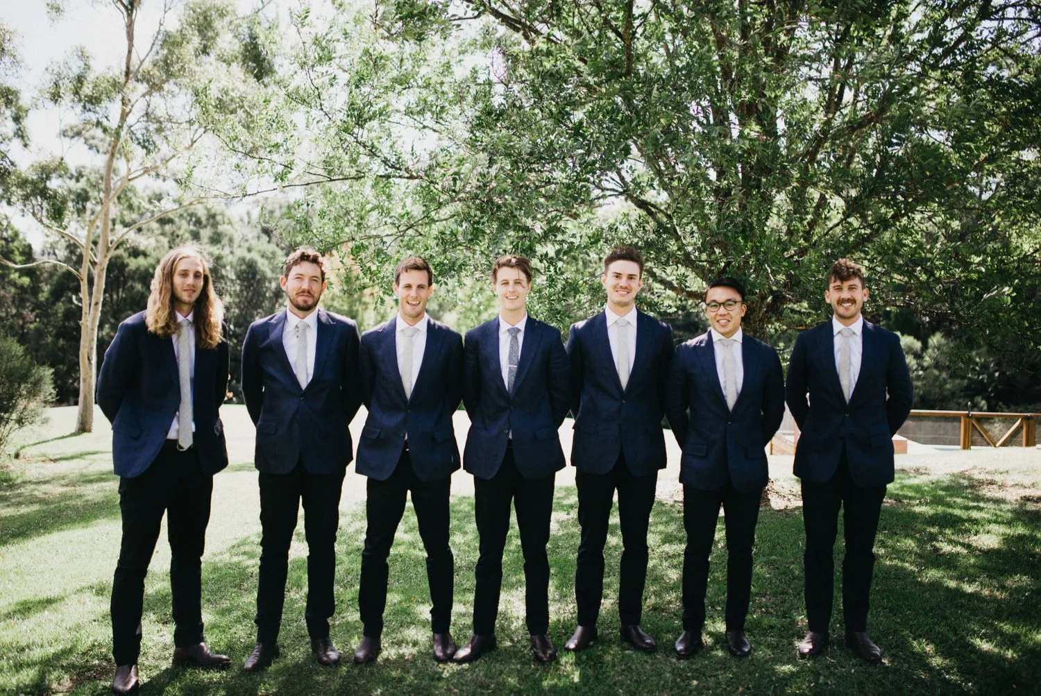 Groomsmen standing in a row on a lawn