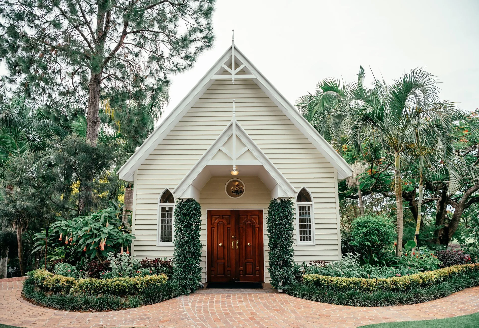 A white timber chapel framed by palms