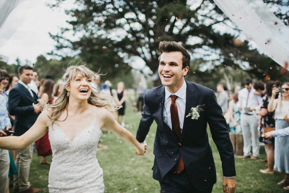 Couple running back down the aisle as guests cheer