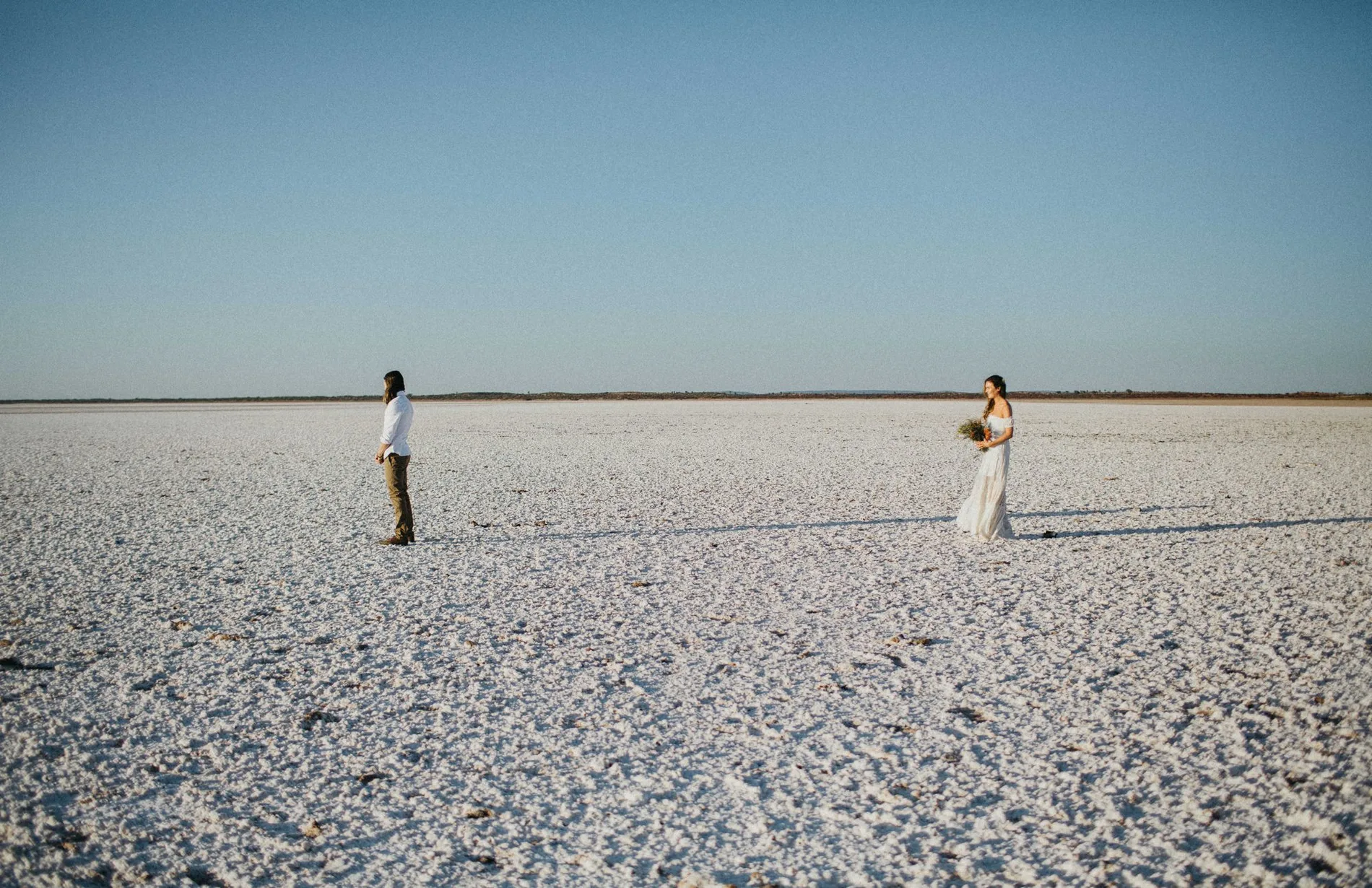 Two tiny figures far apart on a white salt flat