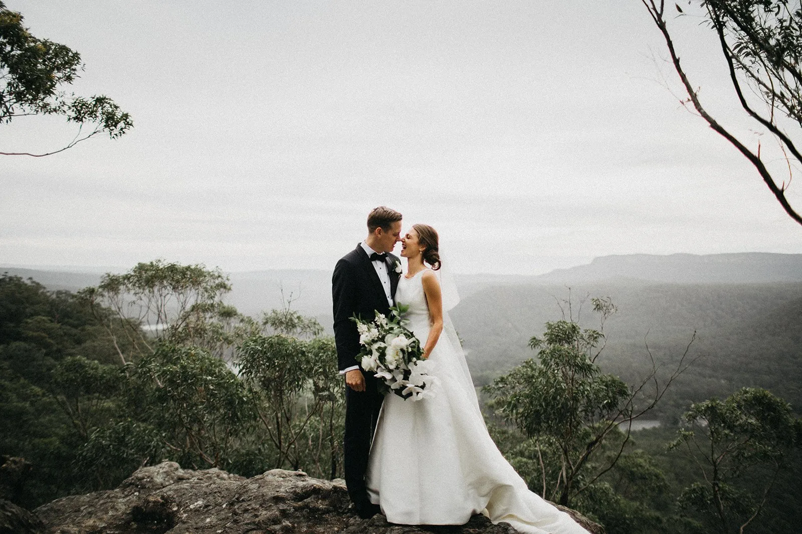 A couple kissing with a mountain range behind them