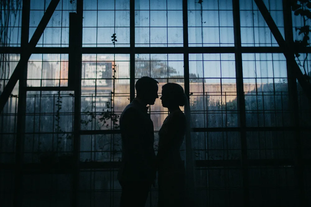 Two silhouettes against a huge factory window