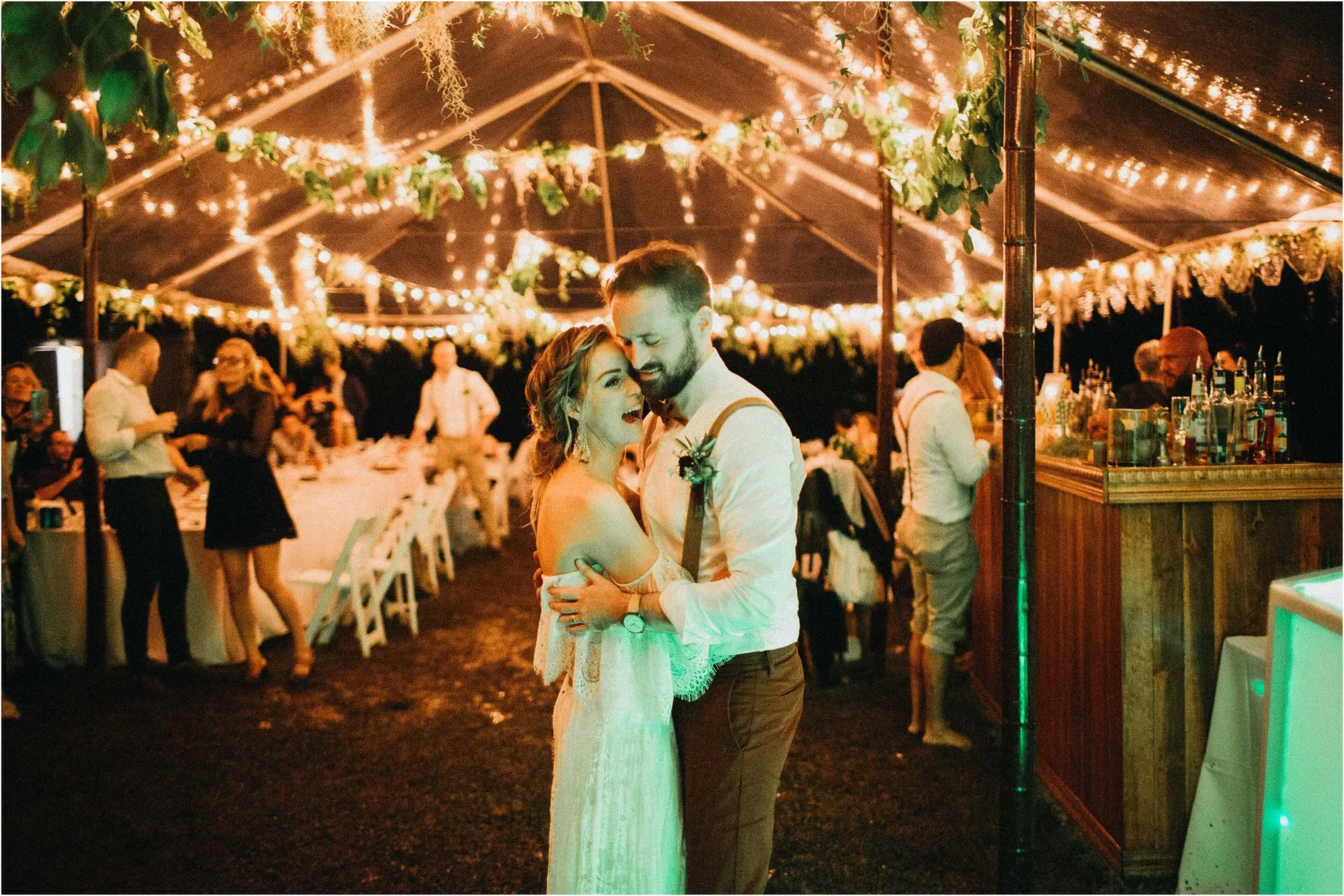 Couple dancing under festoon lights in a marquee